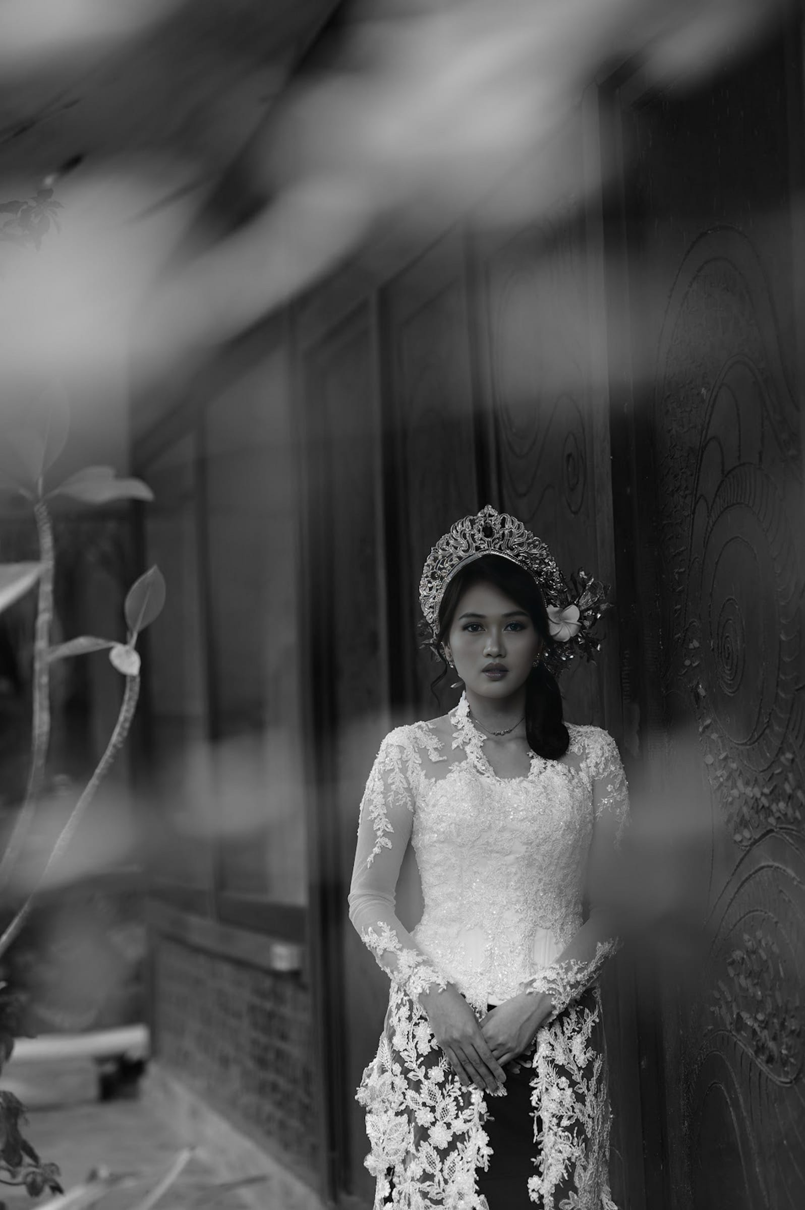 A bride in a fitted beaded kebaya standing with her hands held in front of her.